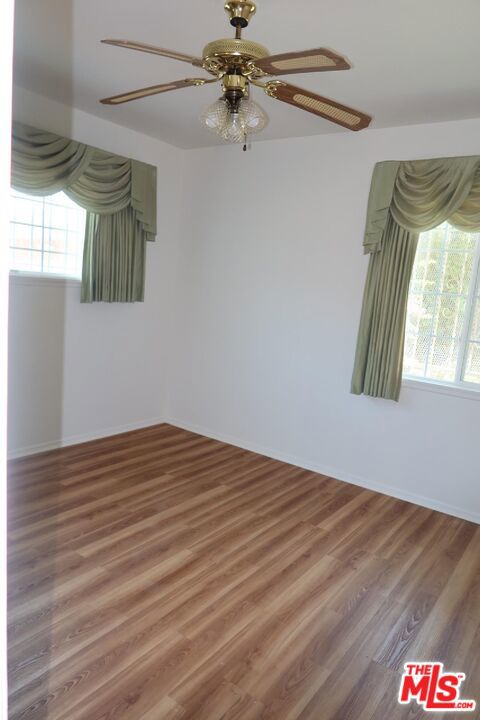 unfurnished room with hardwood / wood-style floors, ceiling fan, and a wealth of natural light