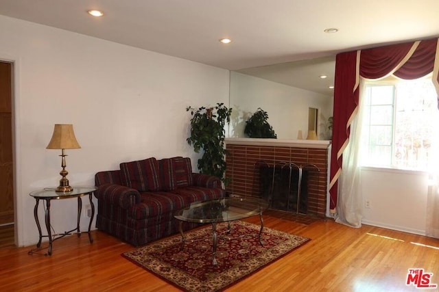 living room featuring wood-type flooring and a brick fireplace