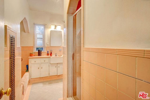 bathroom with vanity, an enclosed shower, and tile walls