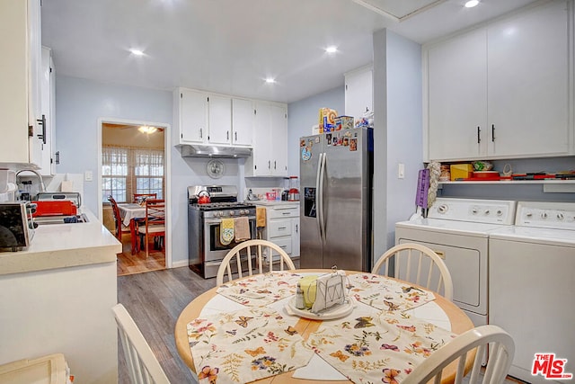 kitchen featuring sink, stainless steel appliances, wood-type flooring, washer and clothes dryer, and white cabinets