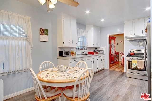 kitchen featuring white cabinets, plenty of natural light, sink, and gas range