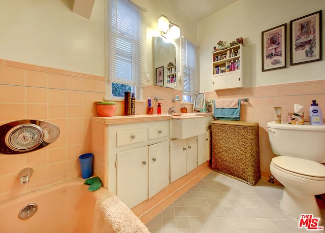 bathroom with vanity, a bathtub, tile patterned floors, toilet, and tile walls