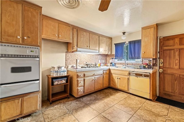 kitchen featuring white appliances, backsplash, sink, ceiling fan, and light tile patterned floors