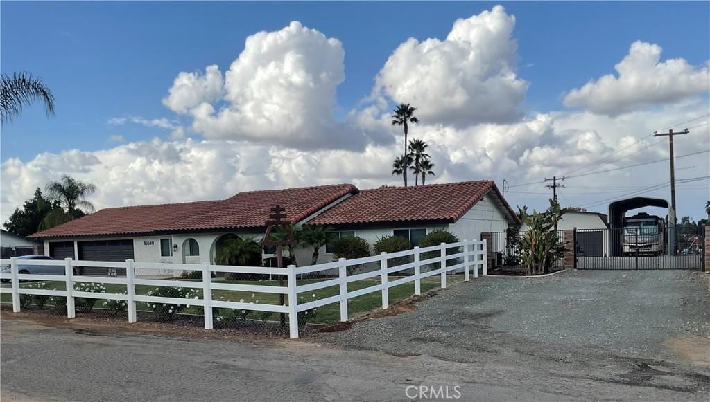 mediterranean / spanish-style home with driveway, a garage, a fenced front yard, a tiled roof, and a gate