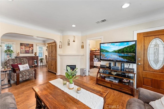 living room with crown molding and light wood-type flooring