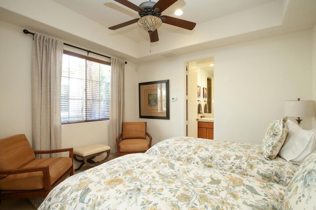 bedroom featuring connected bathroom, a raised ceiling, and ceiling fan