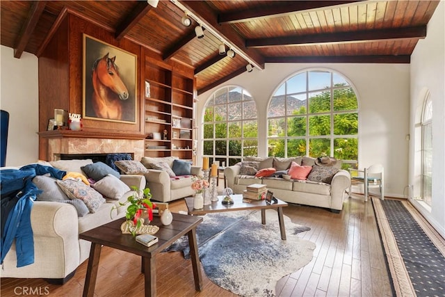 sunroom featuring a high end fireplace, vaulted ceiling with beams, track lighting, and wooden ceiling