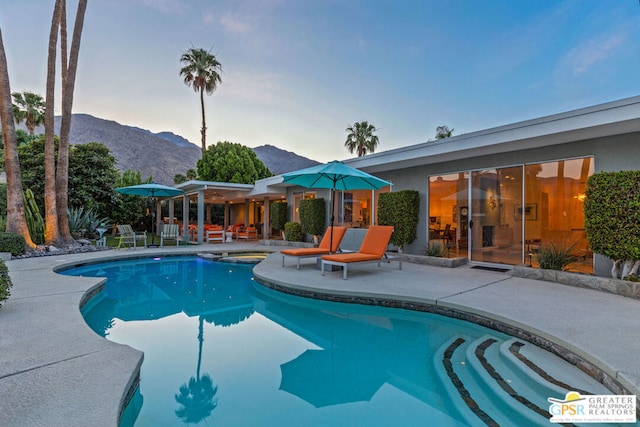 pool at dusk with a mountain view and a patio area