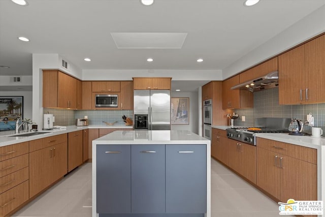 kitchen featuring ventilation hood, sink, built in appliances, tasteful backsplash, and a kitchen island