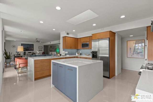 kitchen featuring kitchen peninsula, appliances with stainless steel finishes, tasteful backsplash, ceiling fan, and a center island