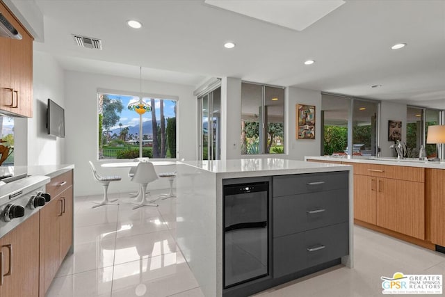 kitchen featuring a center island, sink, beverage cooler, light stone counters, and light tile patterned floors