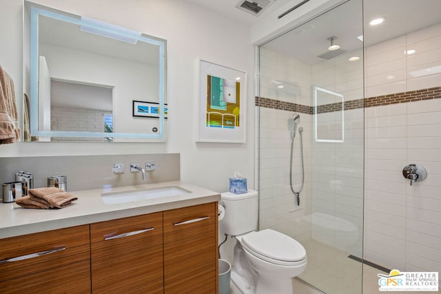 bathroom featuring vanity, toilet, and tiled shower