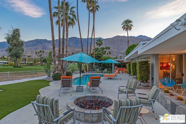 view of patio featuring a mountain view, a fenced in pool, and an outdoor fire pit