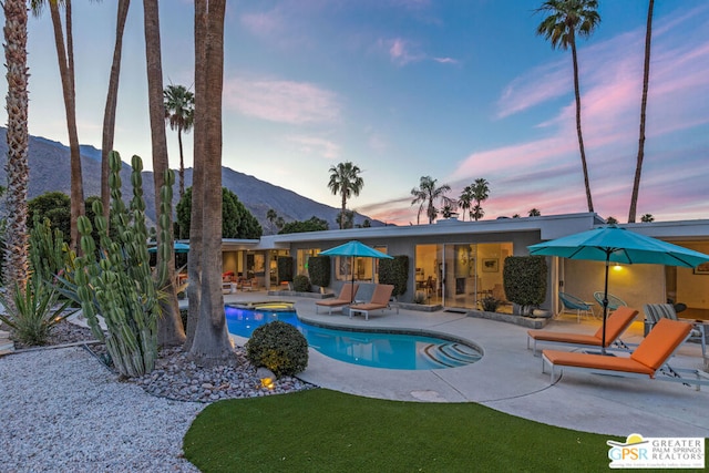 pool at dusk with a mountain view and a patio