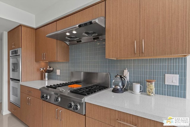 kitchen featuring light stone counters, decorative backsplash, light tile patterned flooring, exhaust hood, and appliances with stainless steel finishes