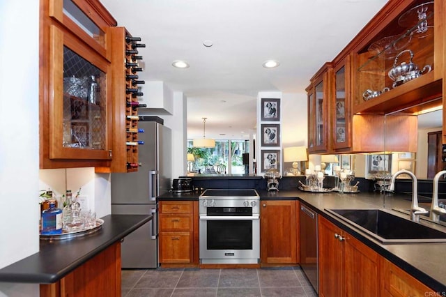 kitchen with sink, appliances with stainless steel finishes, hanging light fixtures, dark tile patterned flooring, and kitchen peninsula