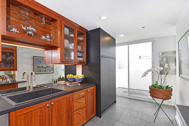 101 Coast Blvd Unit 1C, La Jolla, CA 92037 - kitchen featuring a sink, dark countertops, glass insert cabinets, brown cabinetry, and recessed lighting