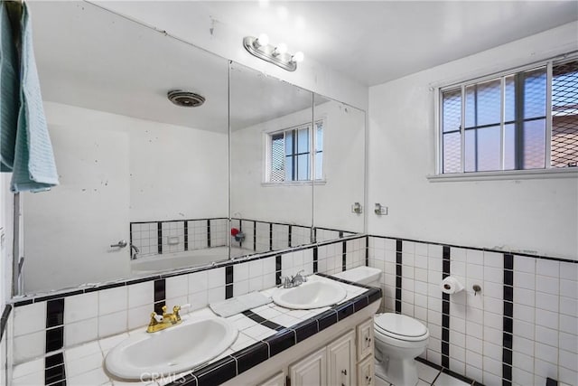 bathroom with toilet, tile walls, a wealth of natural light, and a tub