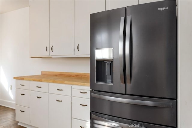 kitchen with white cabinets, stainless steel fridge, hardwood / wood-style floors, and wooden counters