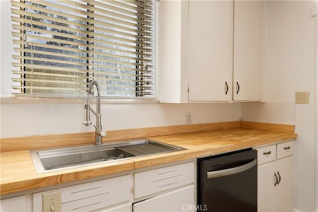 kitchen with wood counters, white cabinetry, dishwasher, and sink