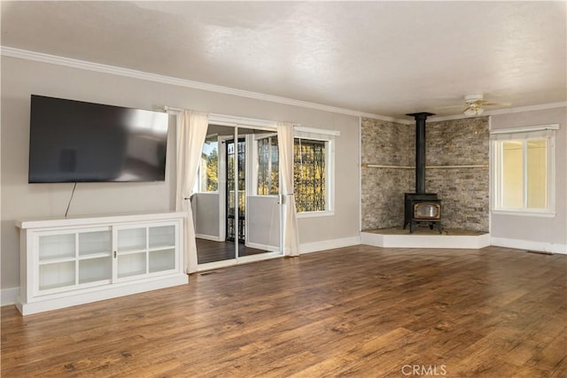 unfurnished living room featuring a wood stove, ceiling fan, hardwood / wood-style floors, and ornamental molding