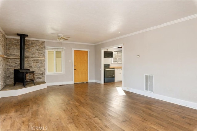 unfurnished living room featuring hardwood / wood-style flooring, a wood stove, ceiling fan, and crown molding