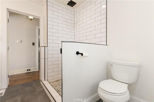 bathroom with a tile shower, toilet, and wood-type flooring