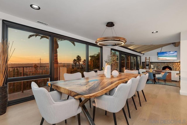 dining room with a fireplace, light hardwood / wood-style floors, and lofted ceiling