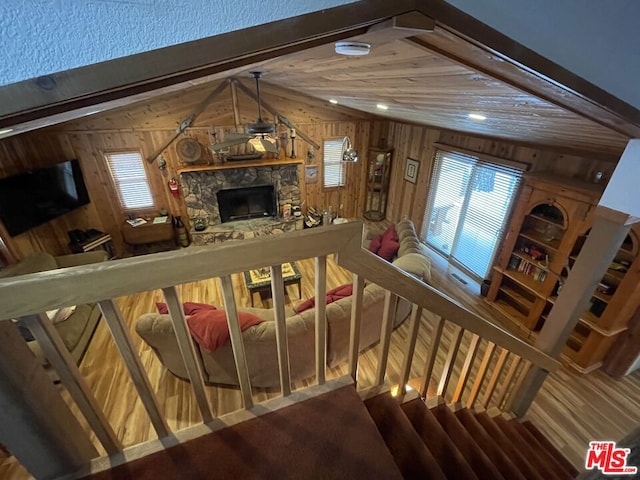 living room featuring lofted ceiling with beams, ceiling fan, a fireplace, and wooden walls