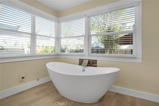 bathroom featuring hardwood / wood-style floors, plenty of natural light, and a bathtub