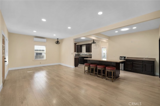 kitchen with an AC wall unit, plenty of natural light, a center island, and a kitchen breakfast bar