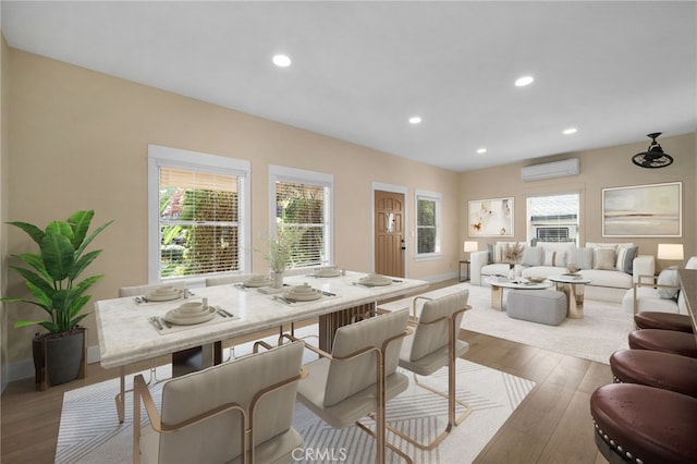 dining room featuring light wood-type flooring, a wall unit AC, and a healthy amount of sunlight