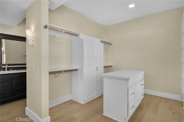 walk in closet featuring light hardwood / wood-style flooring and sink