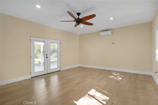 spare room featuring an AC wall unit, ceiling fan, french doors, and light wood-type flooring