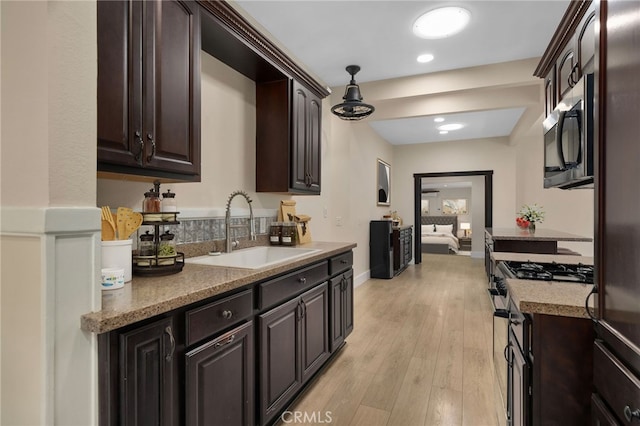 kitchen with hanging light fixtures, sink, light hardwood / wood-style flooring, appliances with stainless steel finishes, and dark brown cabinetry