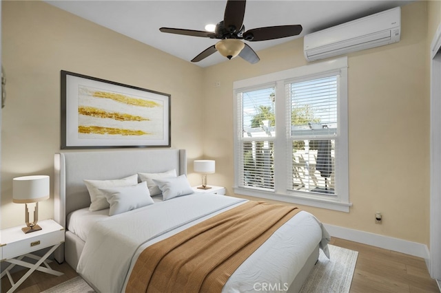 bedroom with a wall mounted air conditioner, ceiling fan, and light hardwood / wood-style floors