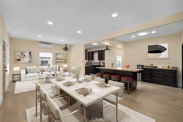 dining room featuring an AC wall unit, plenty of natural light, and light hardwood / wood-style floors