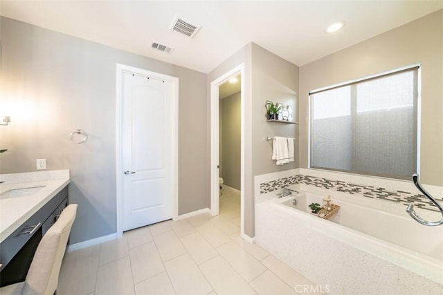 bathroom with toilet, vanity, a tub to relax in, and tile patterned floors