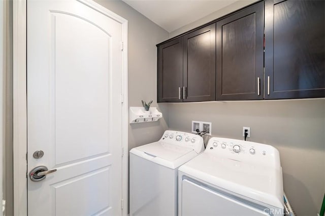 clothes washing area with washer and clothes dryer and cabinets