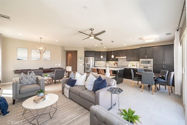 living room with ceiling fan with notable chandelier