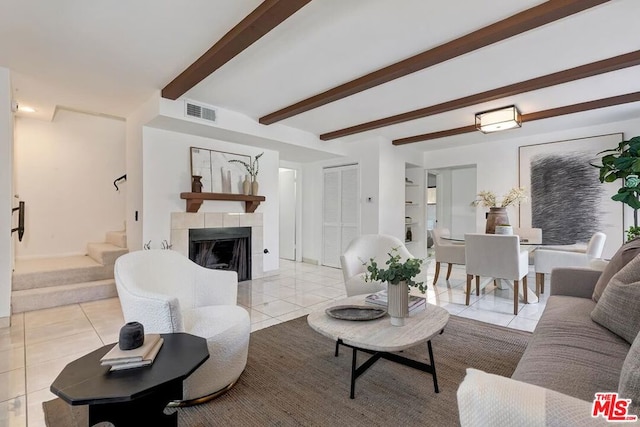 tiled living room featuring beam ceiling and a tiled fireplace