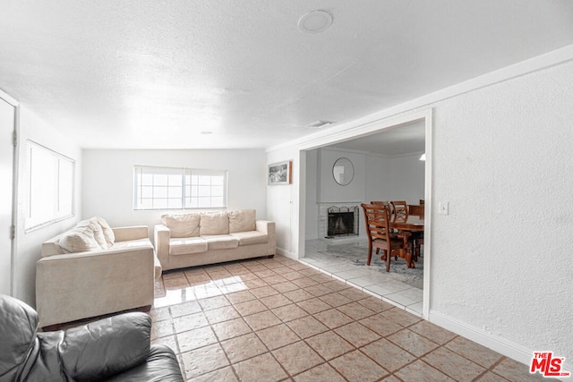 living room with a textured ceiling, light tile patterned flooring, a fireplace, and vaulted ceiling