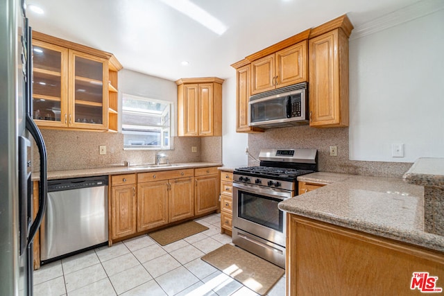 kitchen with sink, light tile patterned floors, ornamental molding, and appliances with stainless steel finishes