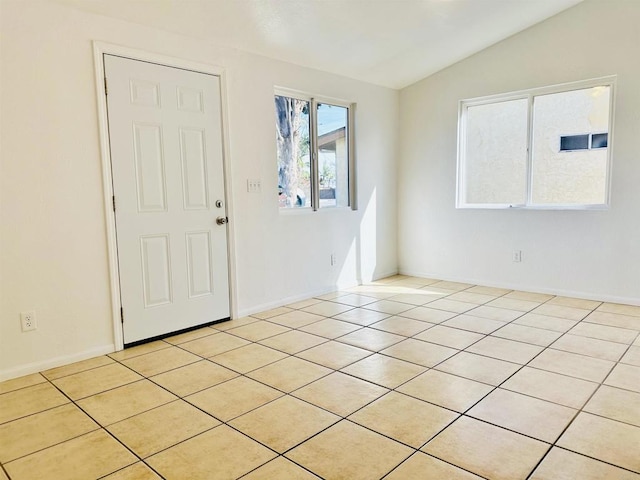 foyer entrance with light tile patterned floors and vaulted ceiling