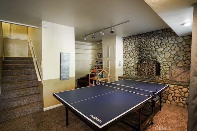 rec room with dark colored carpet, track lighting, and a fireplace