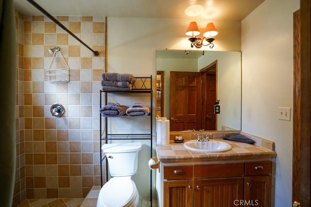 bathroom with tiled shower, vanity, and toilet