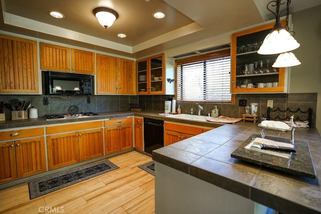 kitchen with sink, light hardwood / wood-style flooring, backsplash, decorative light fixtures, and black appliances