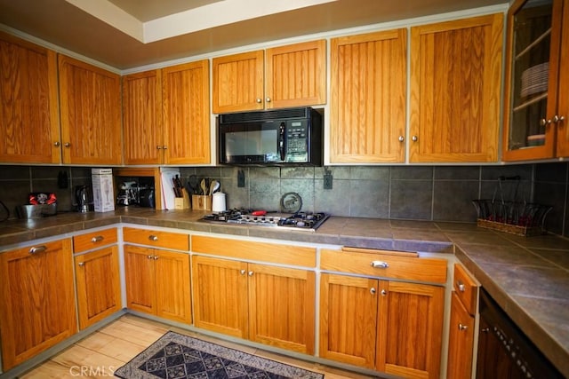 kitchen featuring tile counters, decorative backsplash, stainless steel gas cooktop, and light hardwood / wood-style flooring