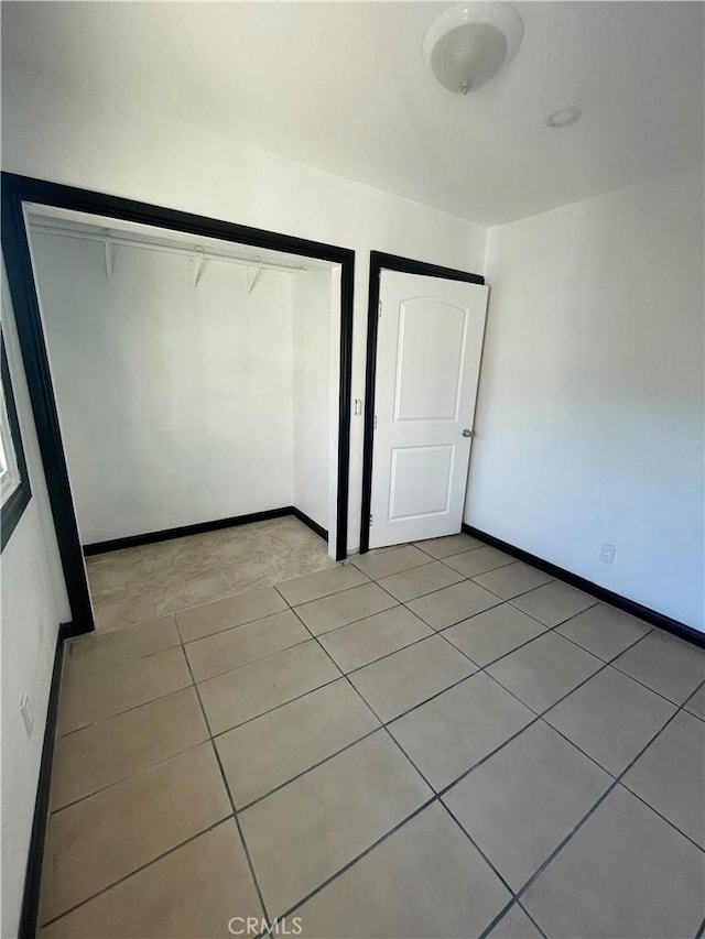 unfurnished bedroom with light tile patterned floors and a closet