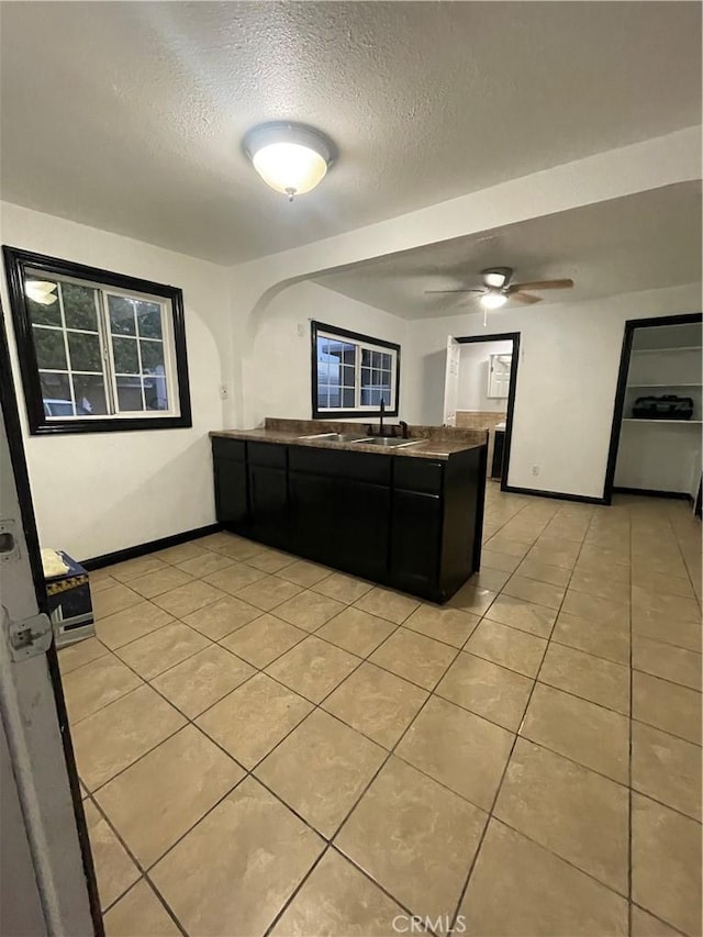 kitchen featuring a textured ceiling, kitchen peninsula, sink, and light tile patterned floors